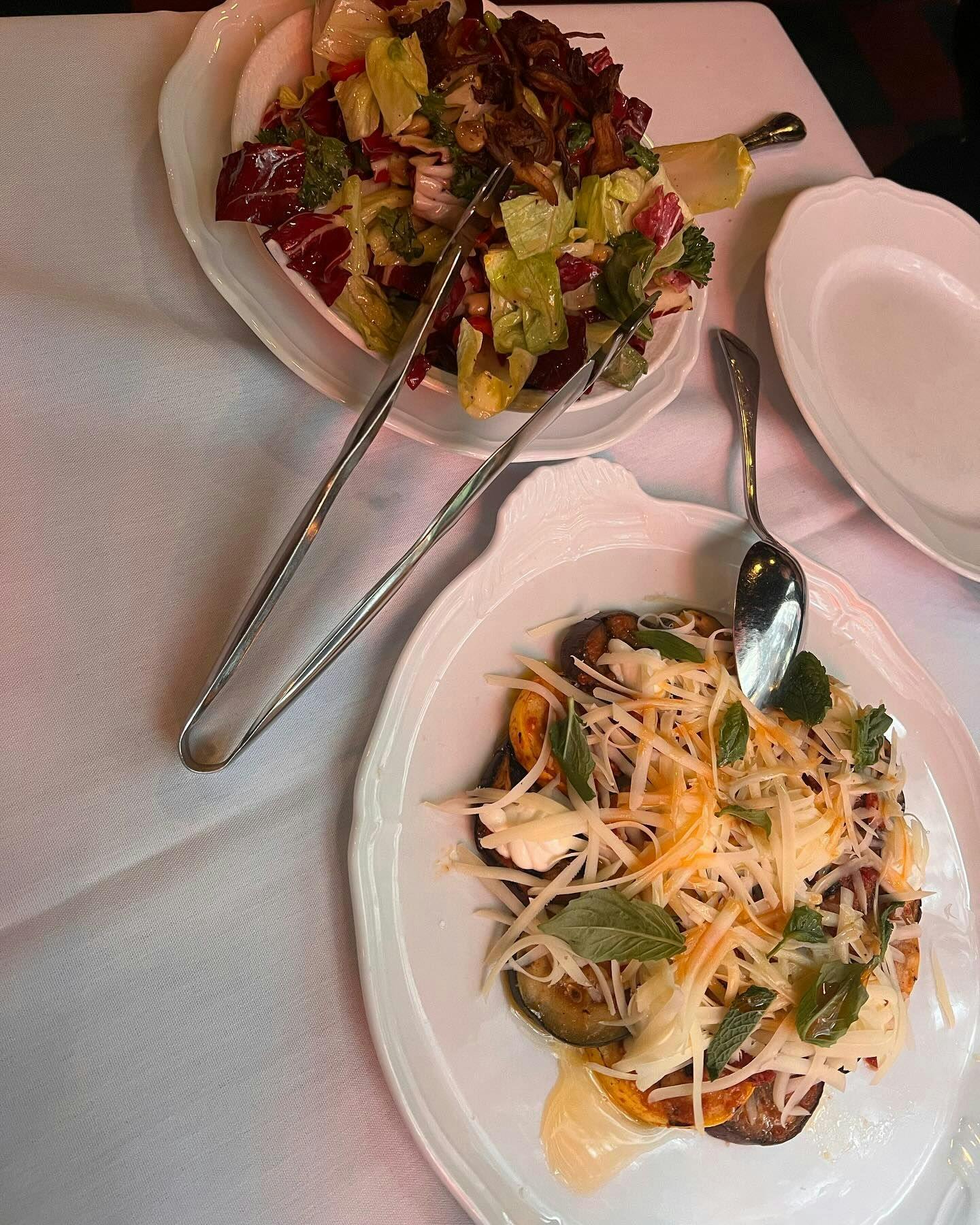Fresh garden salad and a plate of pasta with sautéed mushrooms and grated cheese, served in an elegant dining setting, reflecting the fresh, high-quality ingredients offered by New York's top restaurants on Booked.