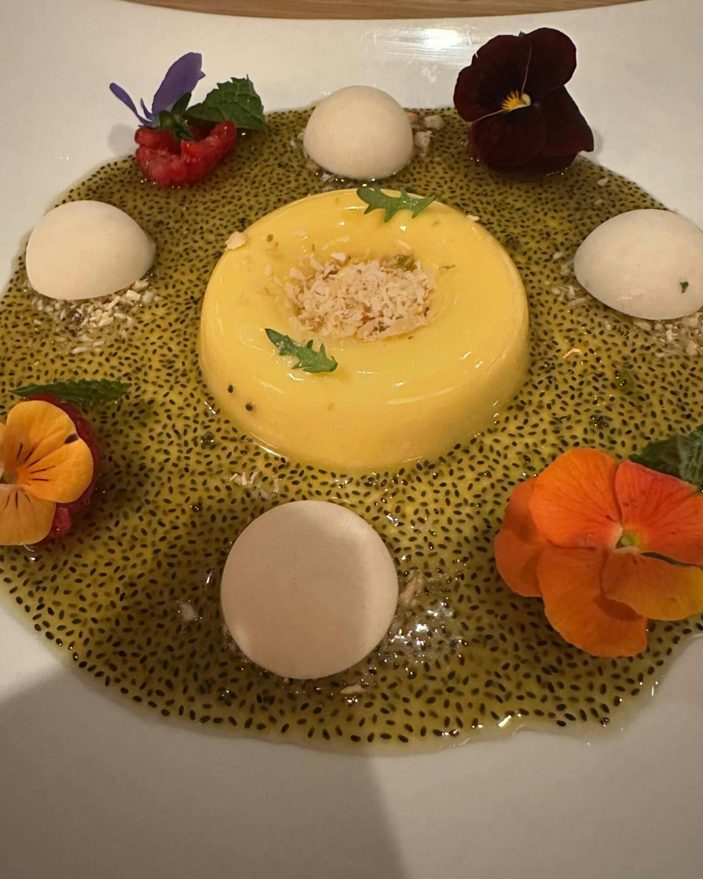 Artistic plating of a passionfruit gelato dessert encircled by edible flowers and a delicate seed garnish, capturing the essence of culinary artistry found in the fine dining experiences available through Booked in New York.