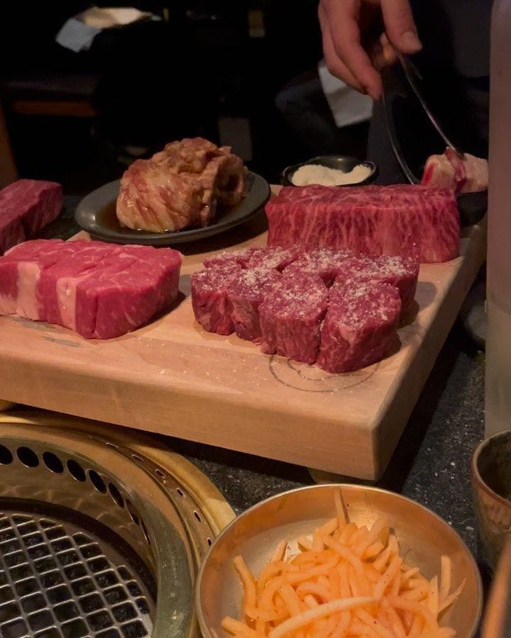 Premium cuts of meat being seasoned with salt, prepared for a Korean BBQ experience, showcasing the interactive culinary adventure that awaits at New York's finest restaurants available through Booked.