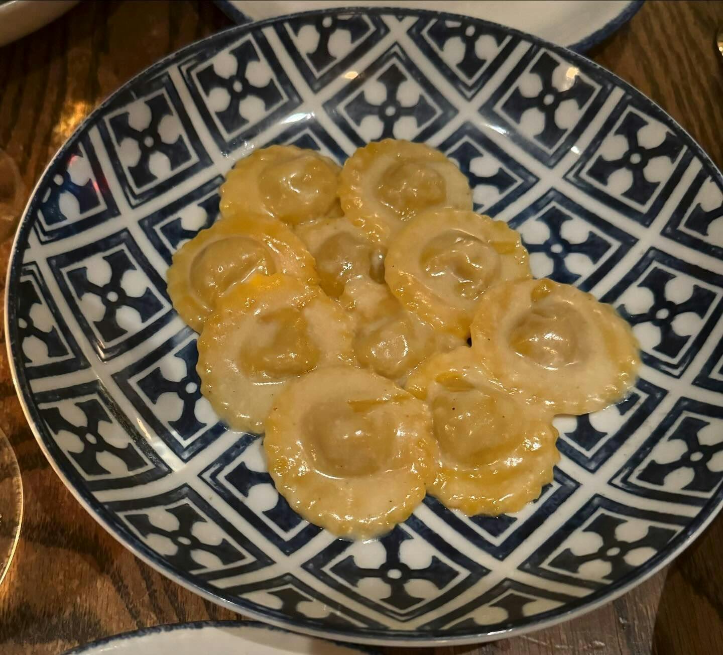 Delicate stuffed pasta served on an ornate blue and white patterned plate, showcasing the art of Italian cuisine available for booking at New York's finest eateries through Booked.