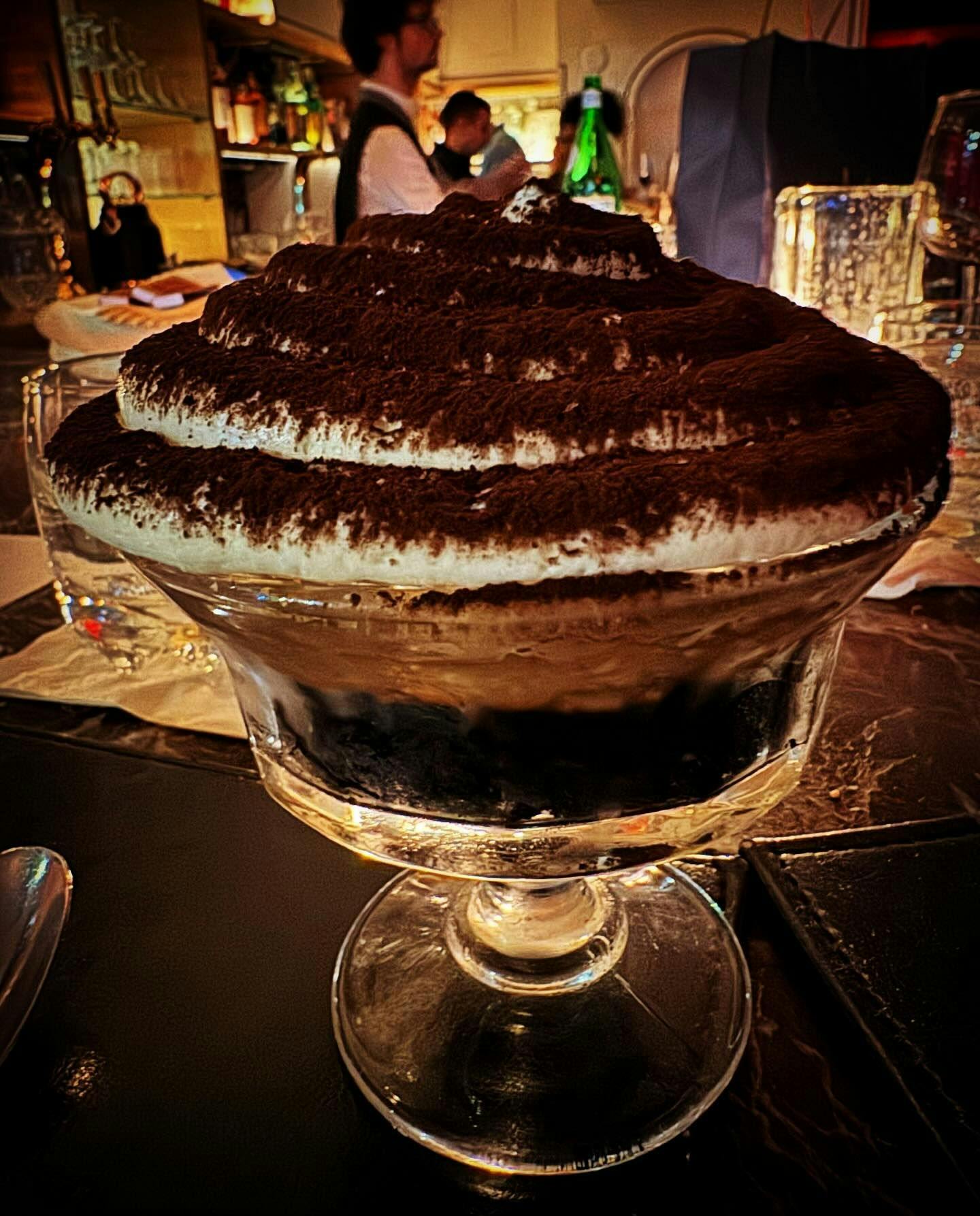 A decadent tiramisu with a generous dusting of cocoa powder, served in an elegant glass dessert bowl, symbolizing the fine desserts that can be enjoyed at the exquisite dining venues New York has to offer through Booked.